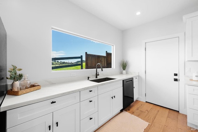 kitchen featuring dishwasher, light wood-style floors, white cabinetry, and a sink