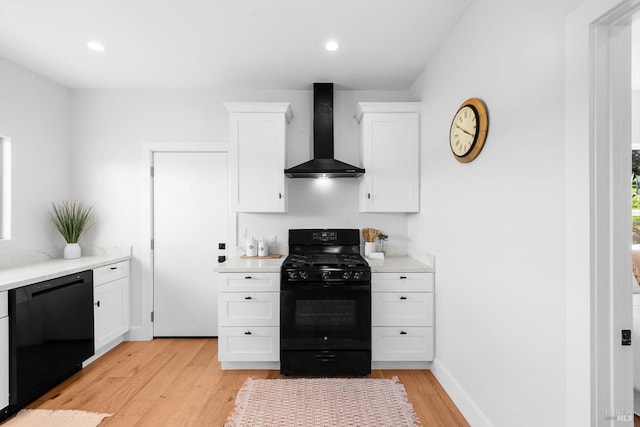 kitchen featuring black appliances, wall chimney range hood, light countertops, and white cabinets