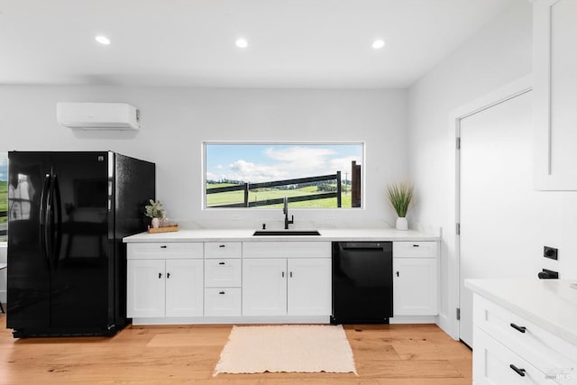 kitchen featuring a sink, black appliances, a wall mounted air conditioner, and white cabinets