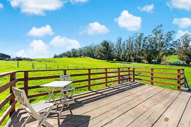 wooden deck featuring a rural view and a yard