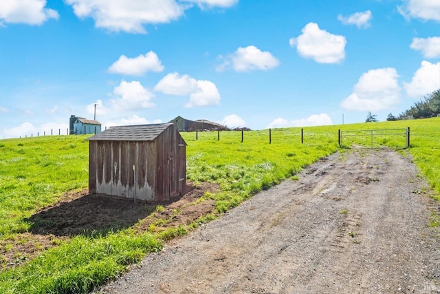 view of yard with a gate, an outbuilding, a rural view, and a shed