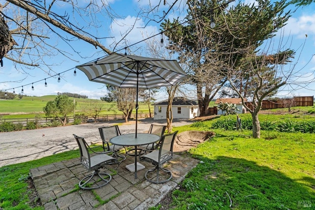 view of yard featuring a patio area, a rural view, an outdoor structure, and fence