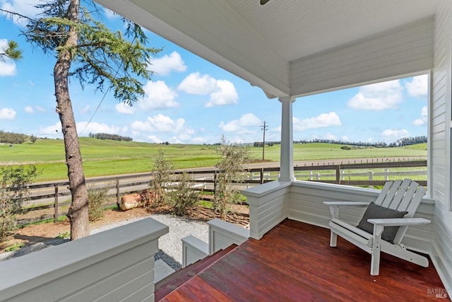 wooden deck with a rural view and fence