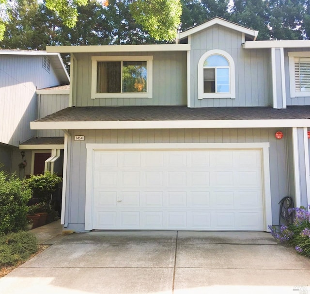 view of front of home featuring driveway, a shingled roof, and an attached garage