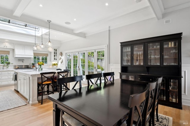 dining room featuring beamed ceiling, visible vents, a wealth of natural light, and light wood-type flooring