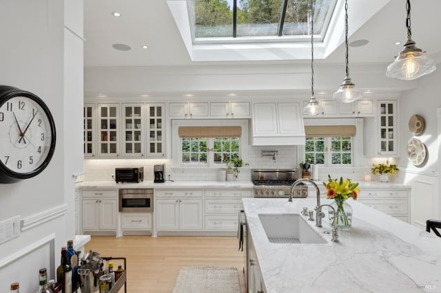 kitchen featuring white cabinetry, a skylight, and a sink