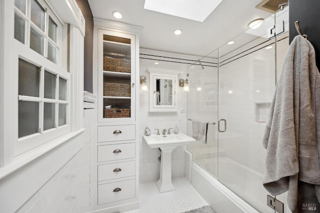 full bathroom with visible vents, bath / shower combo with glass door, recessed lighting, a skylight, and tile walls