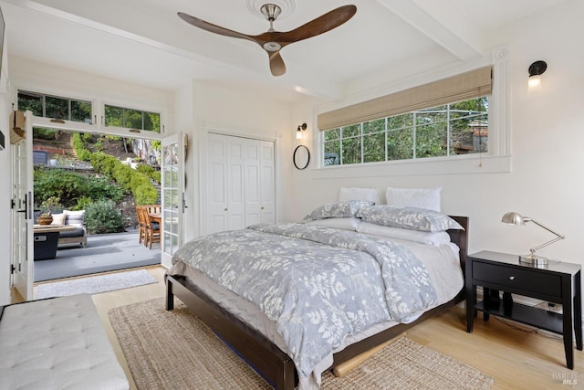 bedroom with wood finished floors, beam ceiling, ceiling fan, a closet, and access to outside