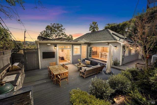 rear view of property featuring a deck, an outdoor living space, fence, and roof with shingles