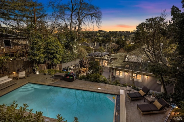 pool at dusk with a fenced in pool, a patio, and a fenced backyard