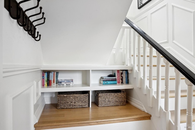 stairs featuring a decorative wall and wood finished floors