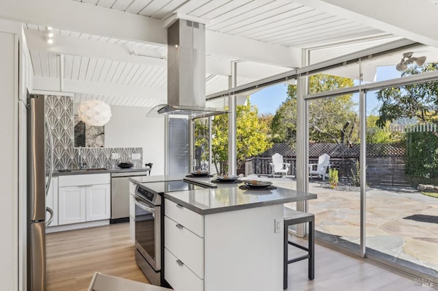 kitchen with a center island, appliances with stainless steel finishes, island exhaust hood, white cabinetry, and a sink