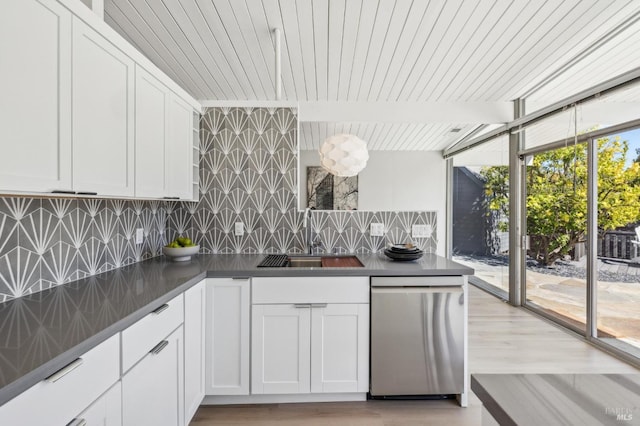 kitchen featuring dark countertops, decorative backsplash, stainless steel dishwasher, white cabinets, and a sink