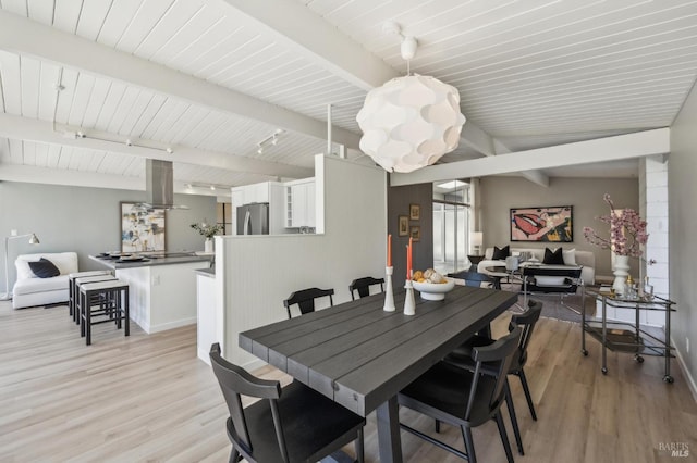 dining space featuring track lighting, light wood-style floors, baseboards, and a chandelier