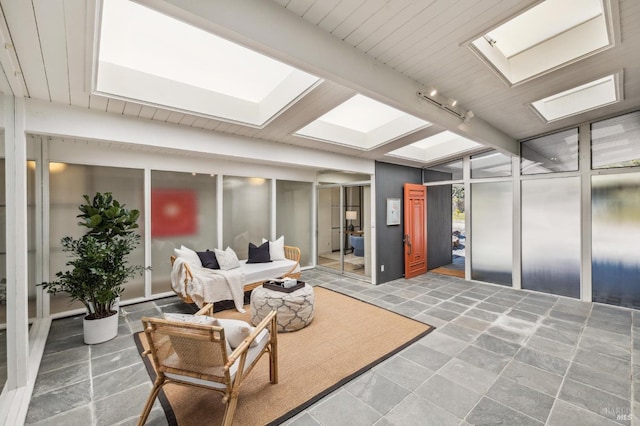 interior space with track lighting, a skylight, elevator, and beamed ceiling