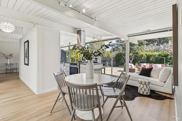 sunroom / solarium with beam ceiling and track lighting