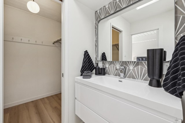bathroom featuring vanity, a spacious closet, wood finished floors, and baseboards