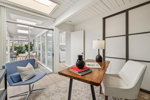 office area featuring beamed ceiling, washer / clothes dryer, a skylight, and wood finished floors