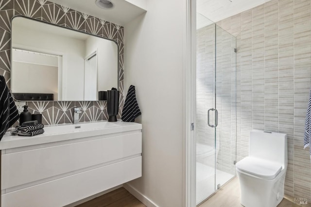 bathroom featuring tasteful backsplash, toilet, vanity, a stall shower, and tile walls