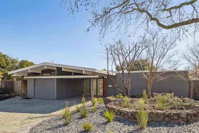 exterior space with an attached carport, fence, driveway, and stucco siding