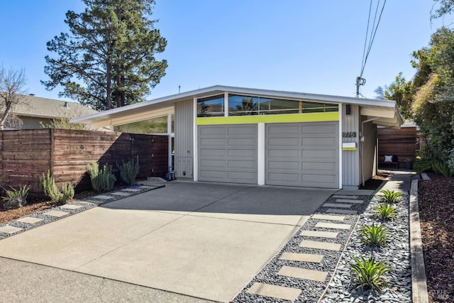 garage featuring concrete driveway and fence