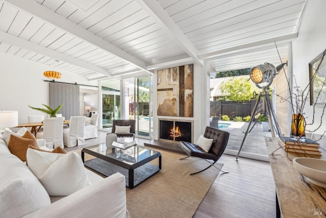 sunroom / solarium with a barn door, beamed ceiling, a fireplace, and a wealth of natural light