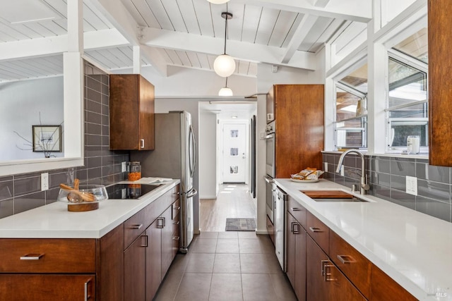 kitchen featuring backsplash, vaulted ceiling with beams, light countertops, and a sink