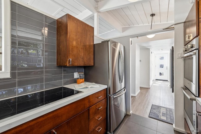 kitchen with beamed ceiling, light countertops, decorative backsplash, tile patterned floors, and black electric cooktop