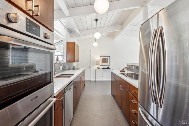 kitchen featuring tile patterned flooring, light countertops, brown cabinets, stainless steel appliances, and a sink