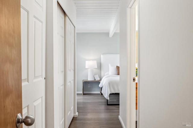 corridor with beamed ceiling, baseboards, and dark wood-style flooring