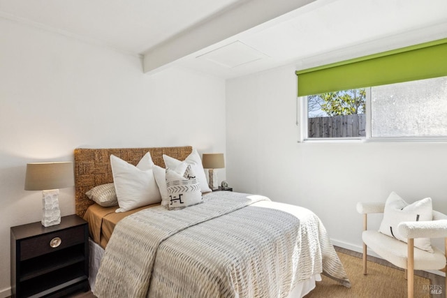 bedroom with beamed ceiling, baseboards, attic access, and wood finished floors