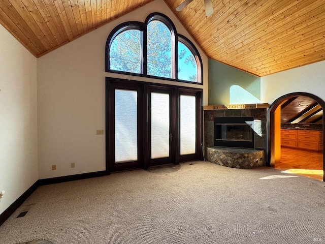 unfurnished living room featuring carpet, a tiled fireplace, and wood ceiling