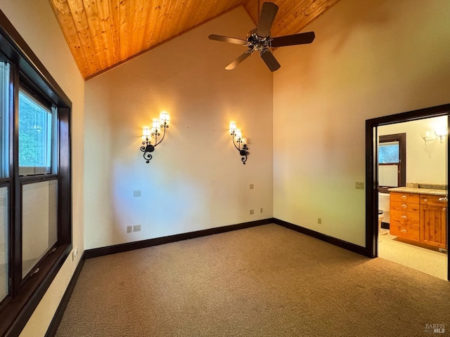 empty room featuring baseboards, light colored carpet, wooden ceiling, and high vaulted ceiling