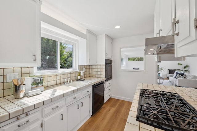 kitchen featuring decorative backsplash, black appliances, tile countertops, and white cabinetry