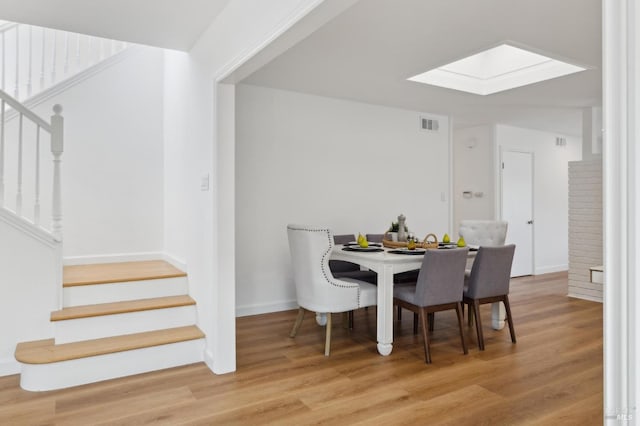 dining area with visible vents, a skylight, stairs, and wood finished floors