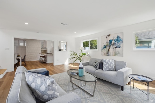 living area with recessed lighting, wood finished floors, visible vents, and baseboards