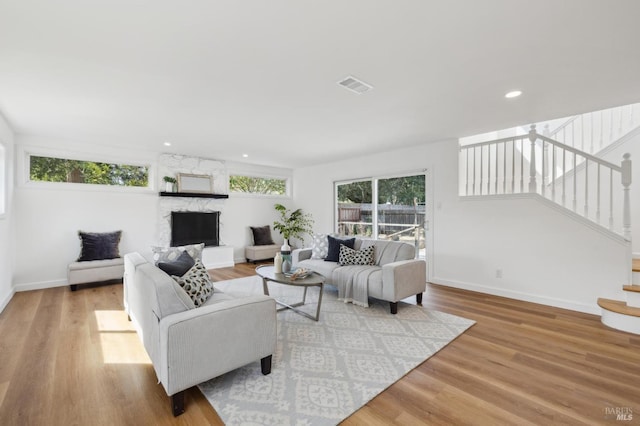 living area featuring stairway, wood finished floors, visible vents, and baseboards