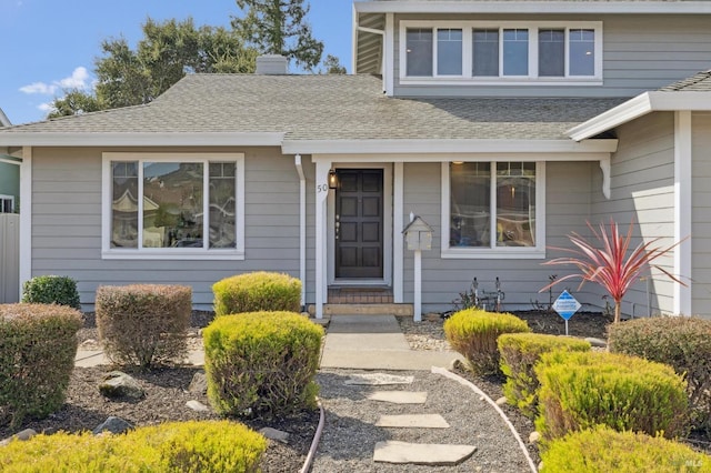 view of front of home with a chimney and a shingled roof