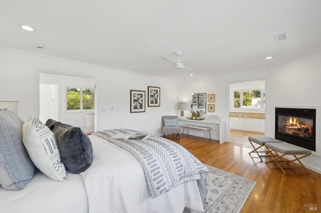 bedroom featuring visible vents, multiple windows, a glass covered fireplace, and light wood finished floors