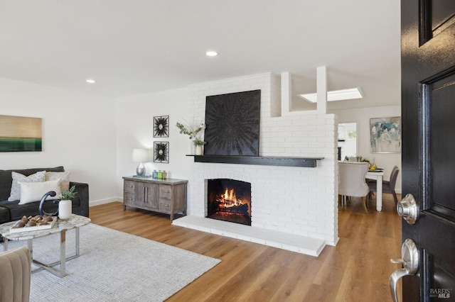 living room featuring recessed lighting, a brick fireplace, baseboards, and wood finished floors