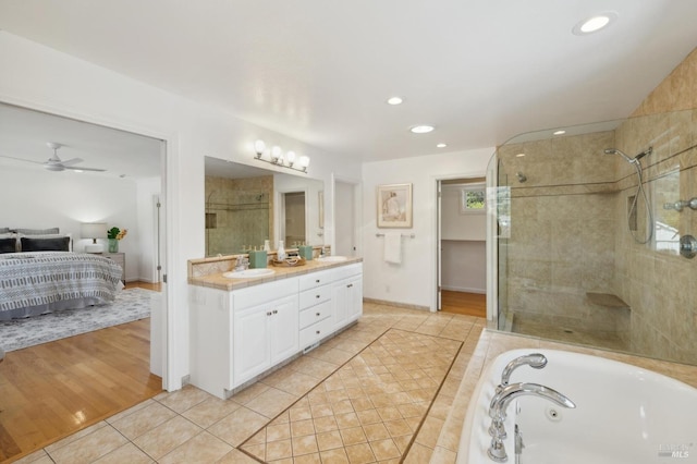 bathroom featuring tile patterned floors, a stall shower, a sink, ensuite bath, and a tub with jets