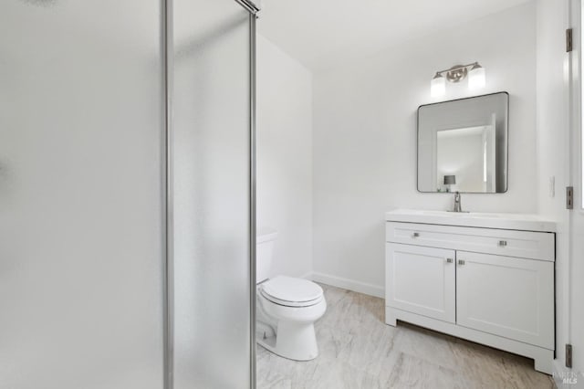 full bath with a shower stall, toilet, vanity, and baseboards