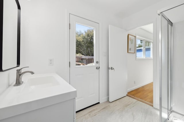 bathroom with baseboards, marble finish floor, and a sink