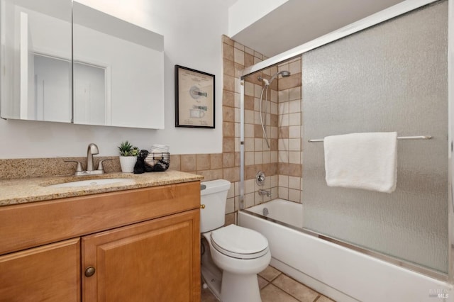 full bath featuring tile patterned flooring, combined bath / shower with glass door, toilet, and vanity