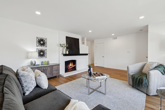 living area featuring recessed lighting, visible vents, light wood-style floors, and a brick fireplace