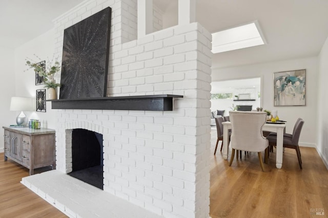 living area featuring a fireplace, baseboards, and wood finished floors