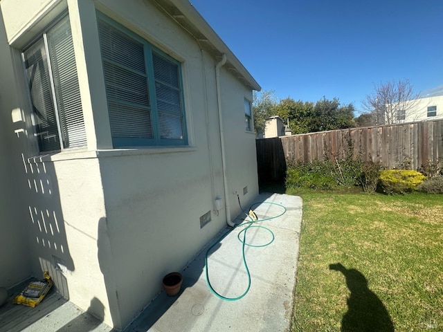 view of side of home with crawl space, a lawn, stucco siding, and fence