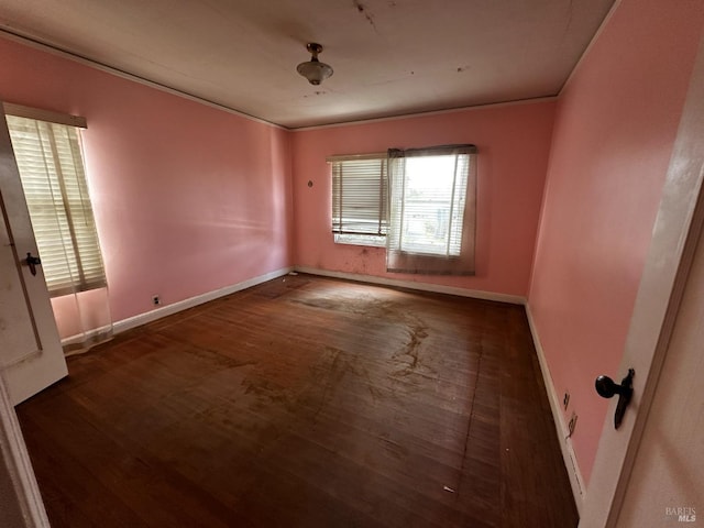 unfurnished room featuring baseboards, wood finished floors, and crown molding