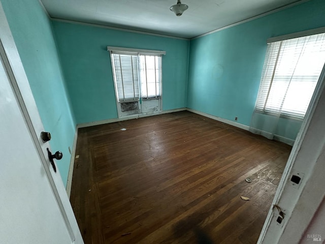 spare room with baseboards, wood finished floors, and crown molding