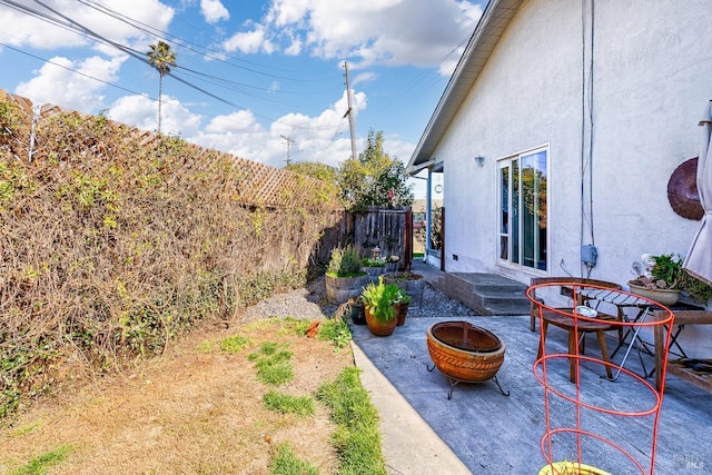 view of yard featuring a patio area, fence, and a fire pit